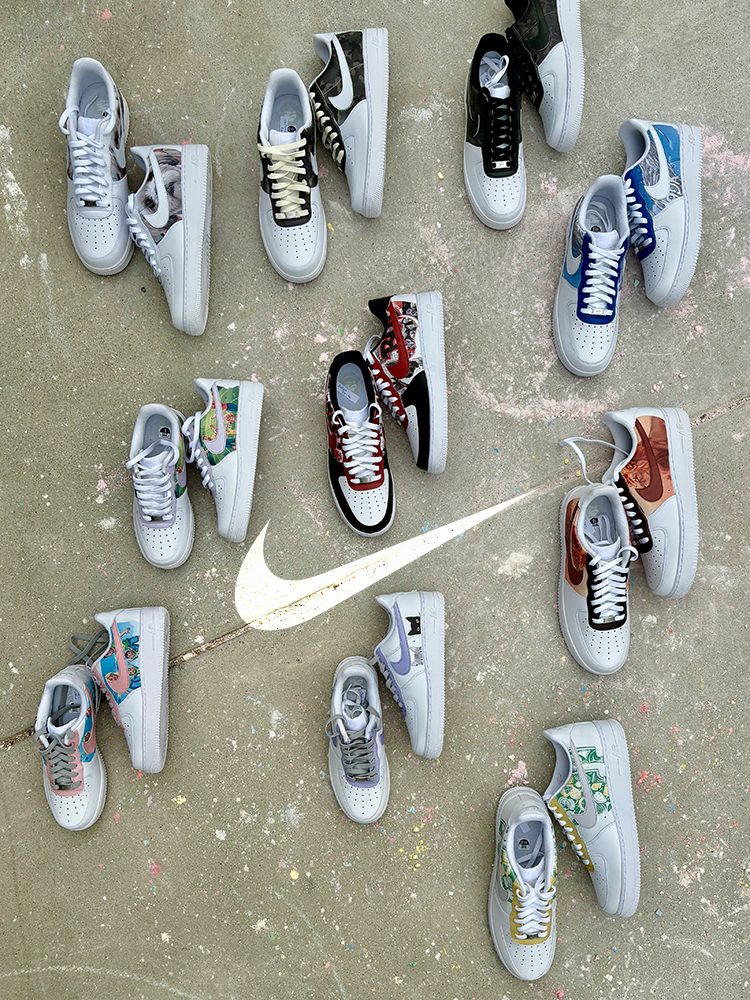 Twelve custom Air Force 1 pairs arranged in a circle around a painted Nike Swoosh on a concrete sidewalk