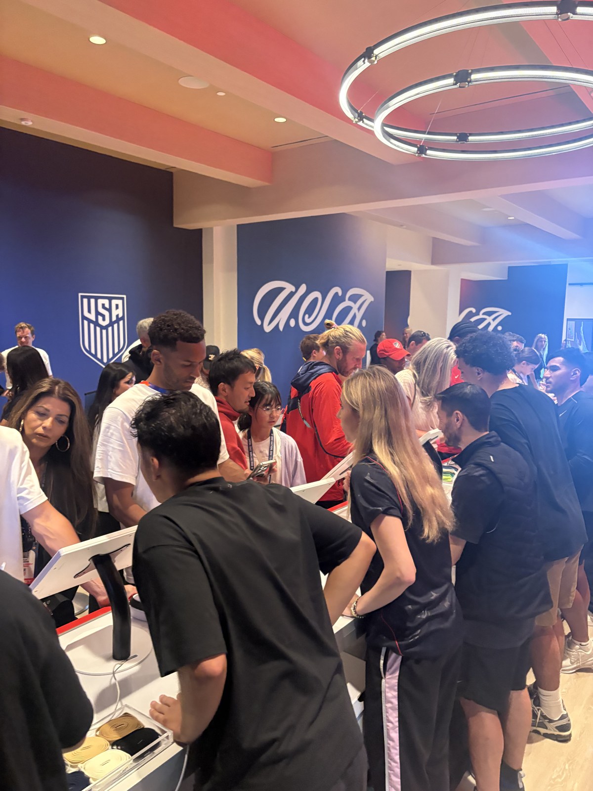 Crowd of athletes and guests gathered at U.S. Soccer design kiosks during the 1ofONE activation