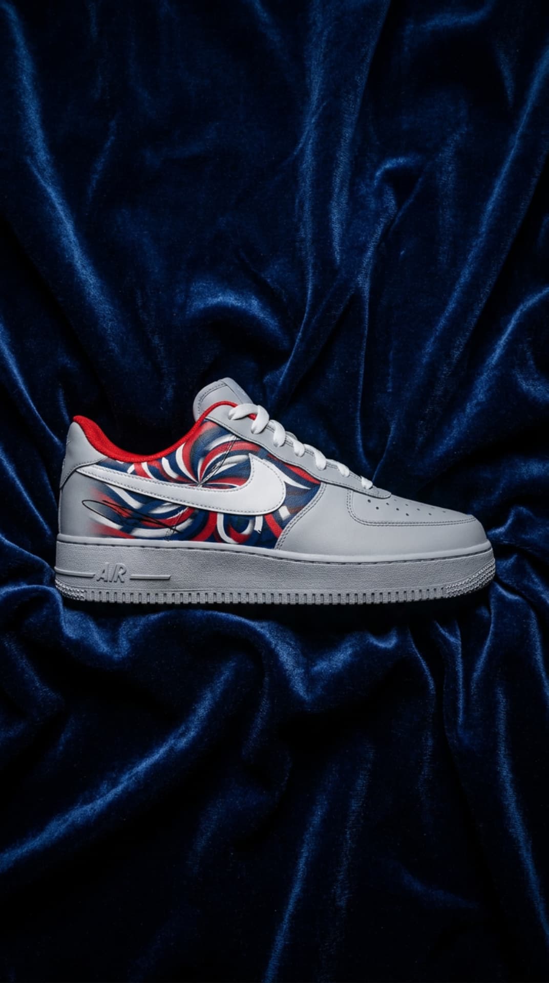 White Air Force 1 with a red, white and blue swirl panel resting on deep blue velvet