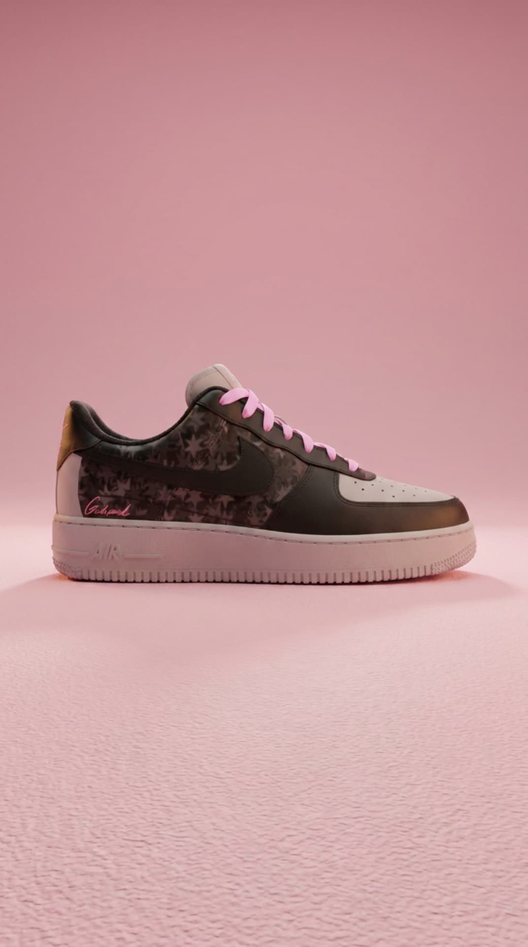 Black Air Force 1 with a star-print panel and pink laces on a soft pink textured floor