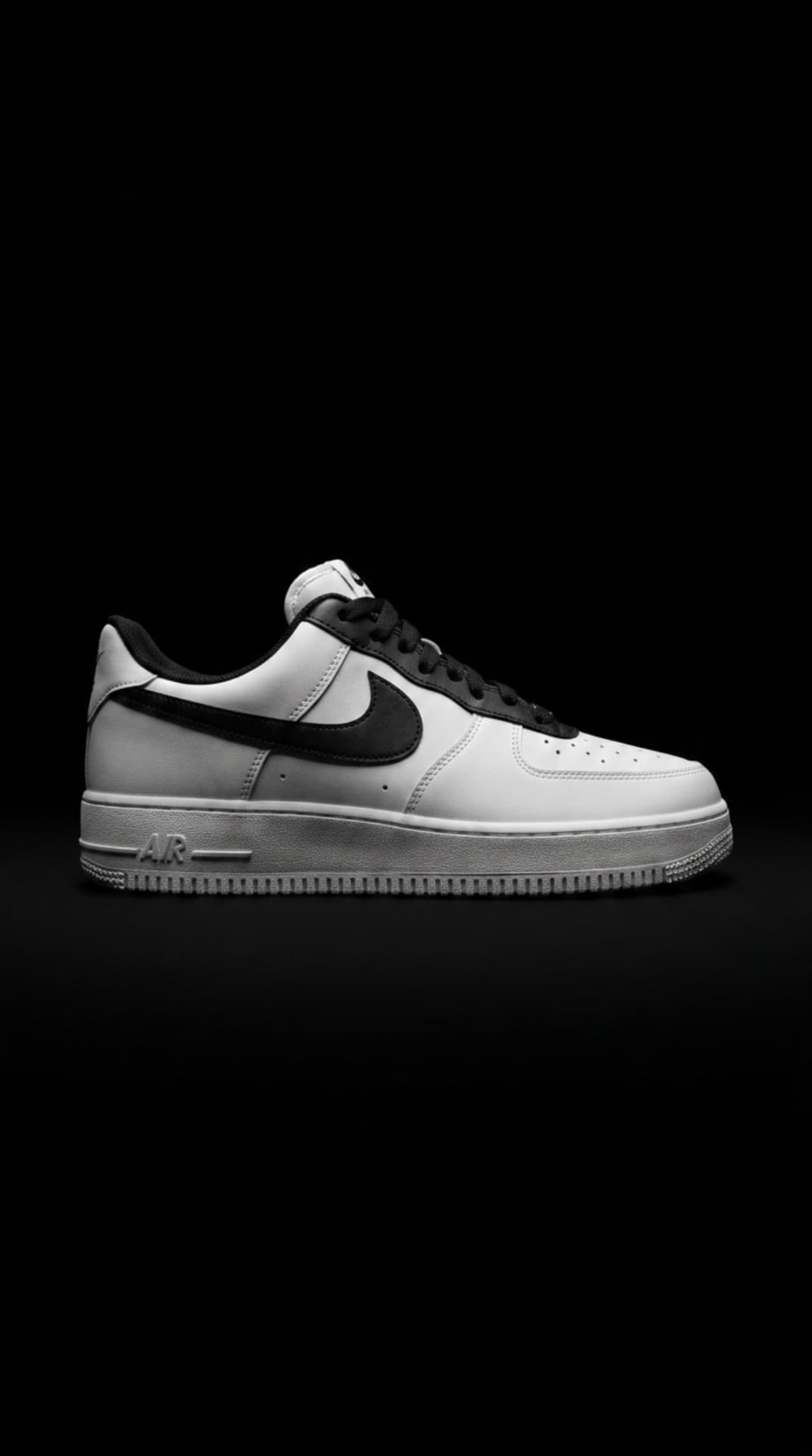 White Air Force 1 with a black swoosh and black laces against a deep black void backdrop