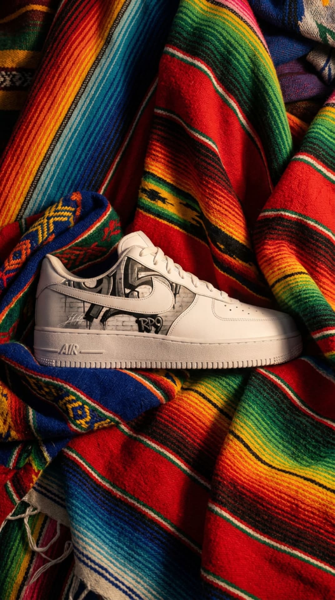 The graffiti-panel Air Force 1 resting on a brightly striped serape blanket