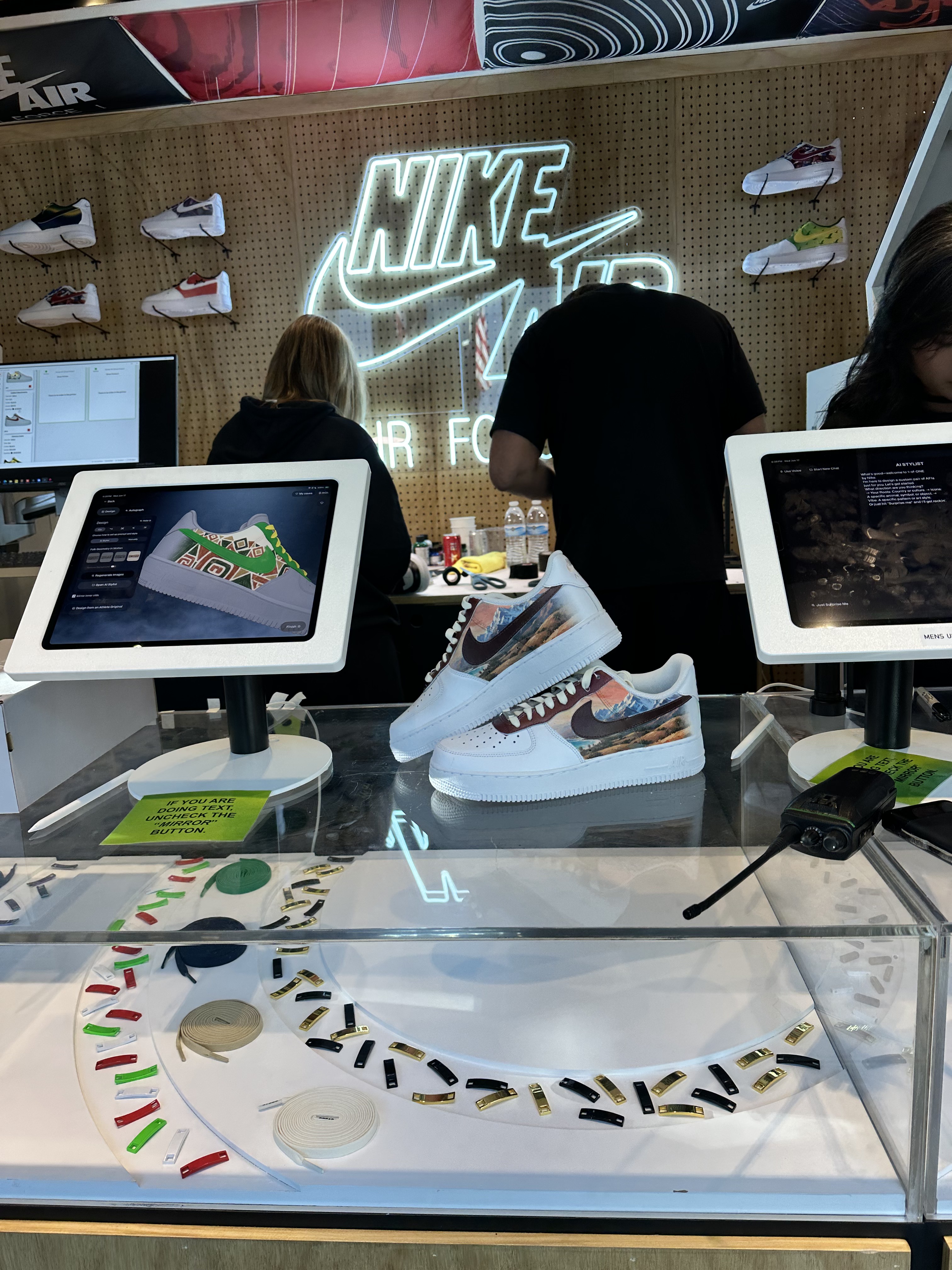 Design kiosks and finished mountain-print Air Force 1s on the counter under a Nike Air neon sign