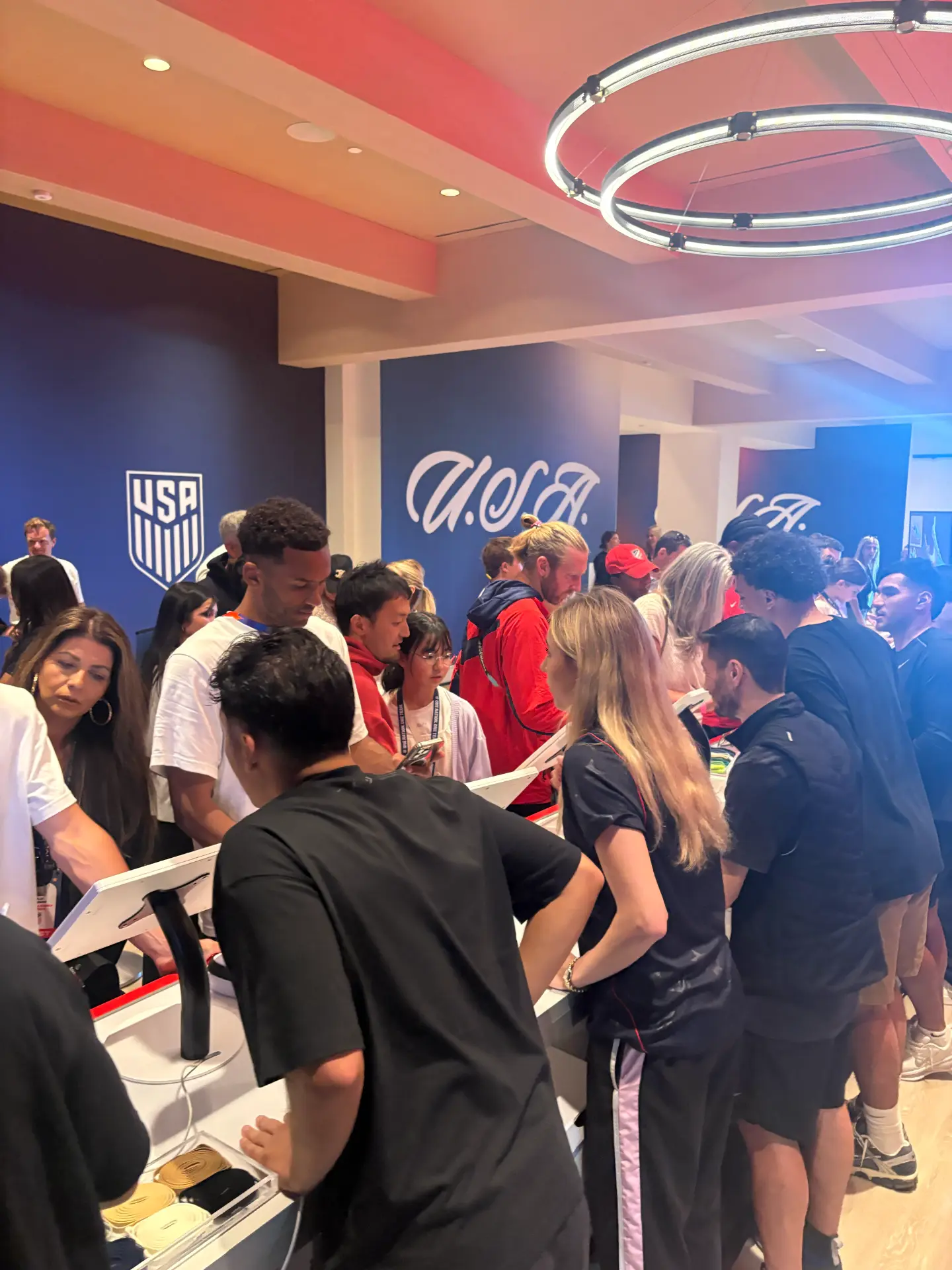 Crowd of athletes and guests gathered around the customization stations inside the U.S. Soccer activation space