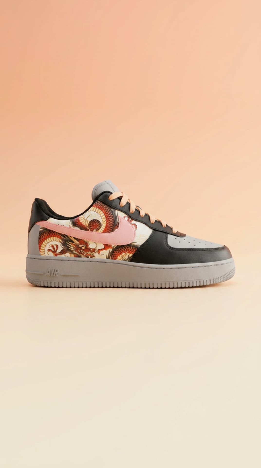 Black and grey Air Force 1 with a red dragon print panel and pink swoosh against a peach gradient backdrop