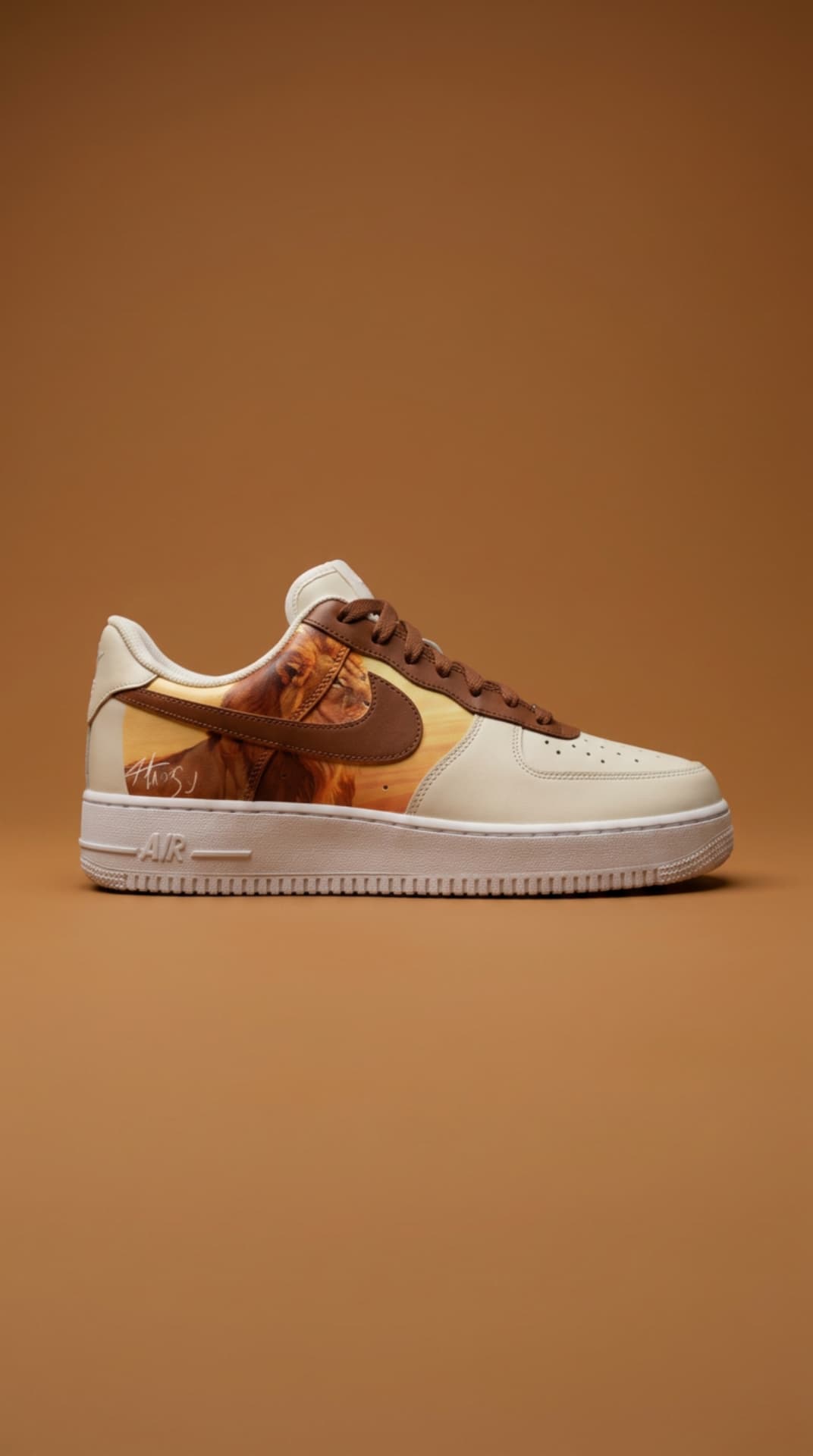 Cream Air Force 1 with a lion panel and brown swoosh against a warm tan backdrop
