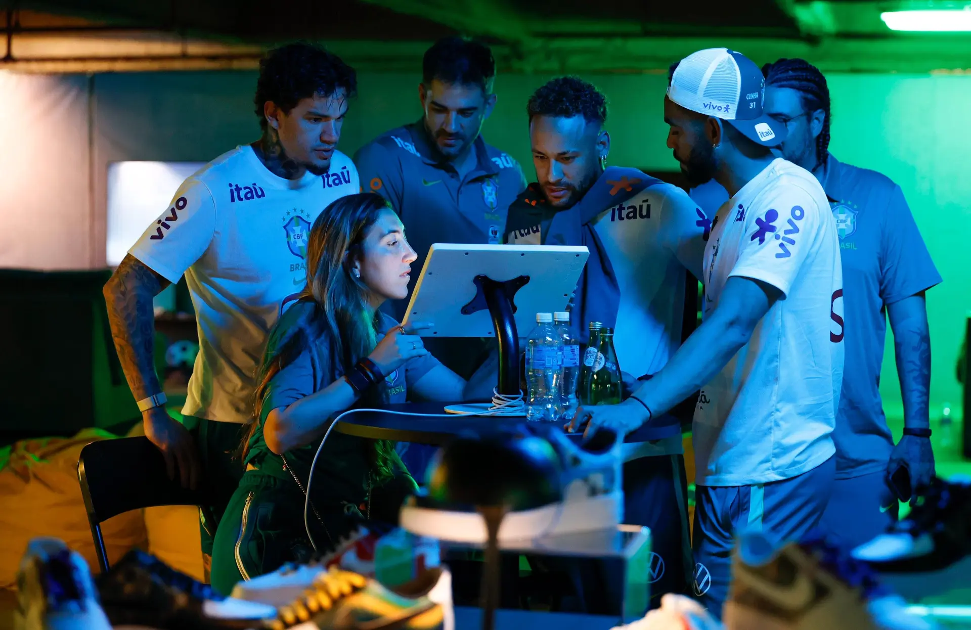 Brazil athletes gathered around a tablet designing their AF1s under green and blue light