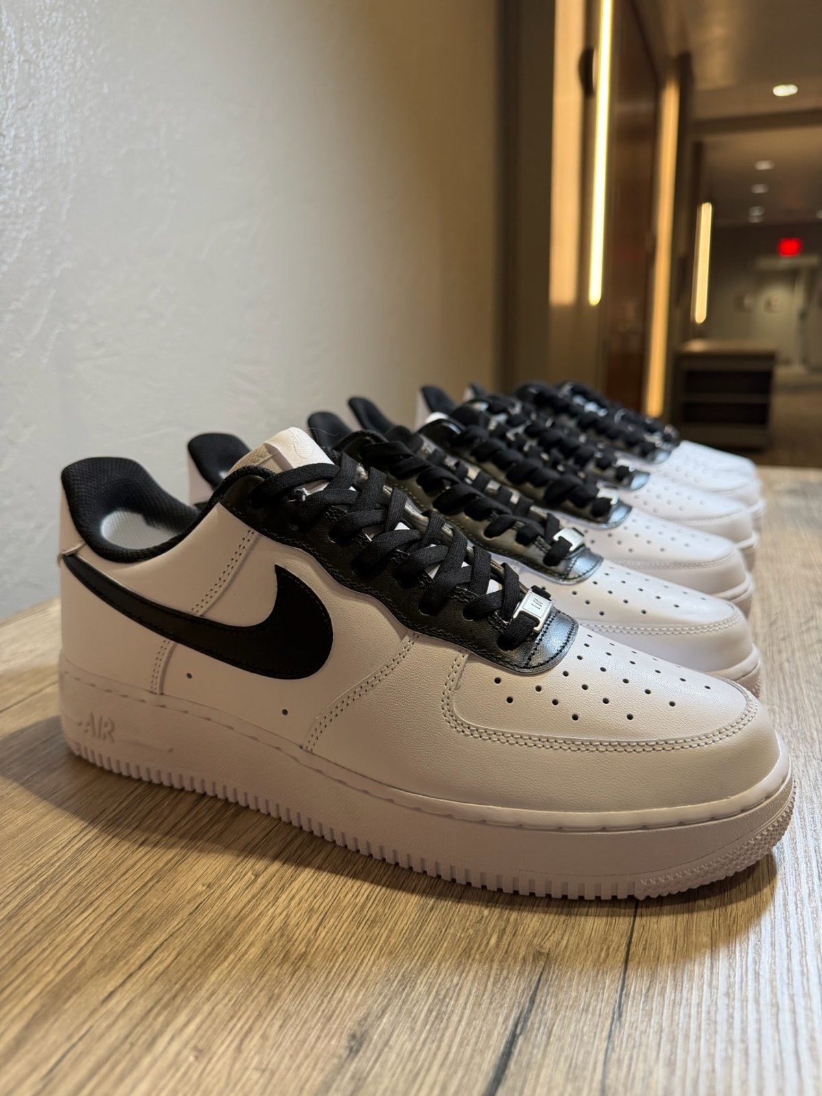 Row of blank white Air Force 1s with black swooshes and laces lined up before customization