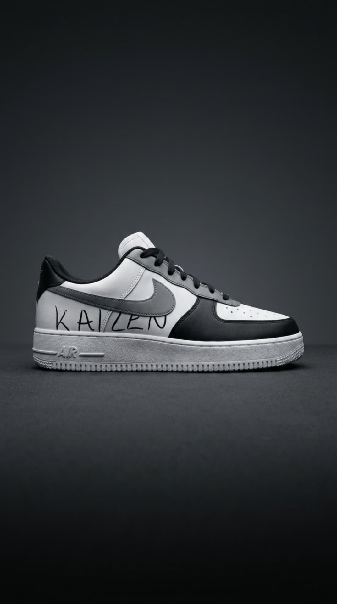 White, grey and black Air Force 1 with handwritten KAIZEN script on the panel against a dark smoke backdrop
